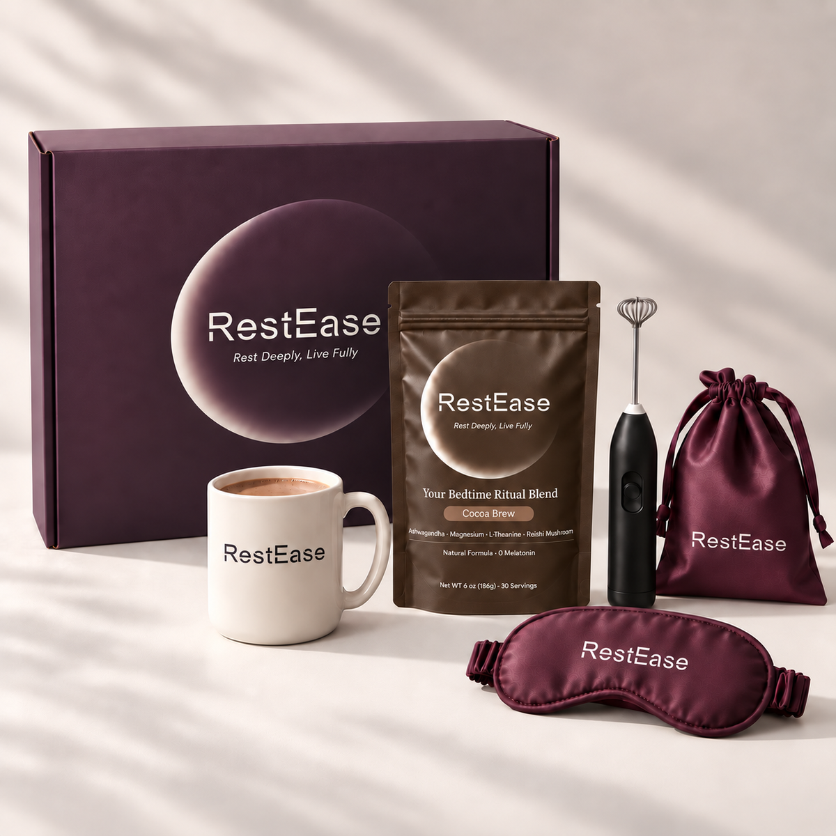 RestEase Cocoa Brew arranged on a light neutral surface with soft shadows, including a large dark plum gift box, a white mug with RestEase branding, a brown ritual blend pouch, a black handheld frother with whisk attachment, a dark plum drawstring pouch, and a matching plum sleep mask.