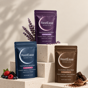 RestEase Bedtime Ritual Blends are arranged on beige stone blocks with decorative lavender, berries, and cocoa powder. The pouches are purple, navy blue, and brown, representing different flavor options.