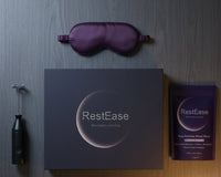 RestEase sleep aid product set including eye mask, box, and packets on a wooden surface.
